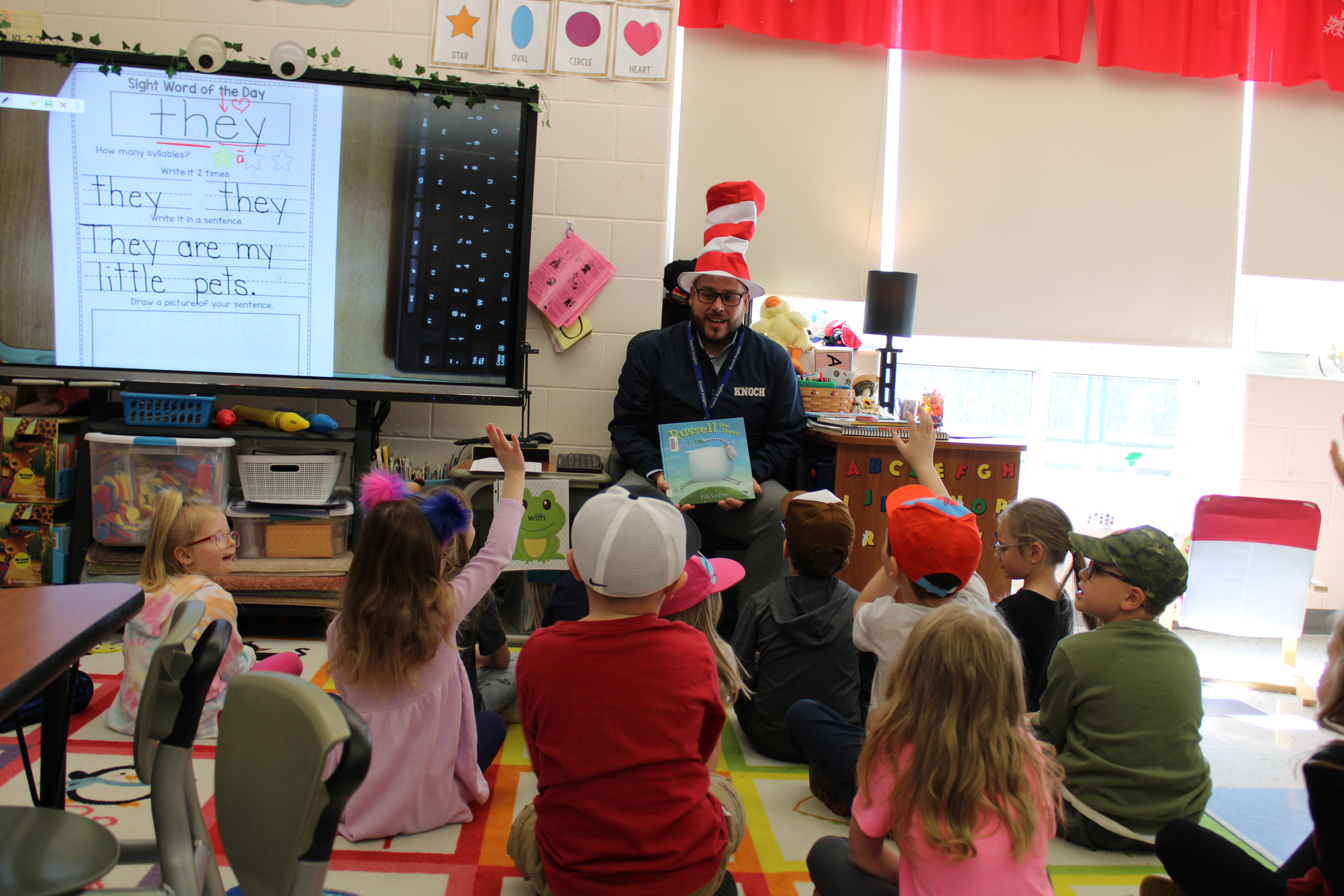 principal in a Dr. Seuss hat reading to kids
